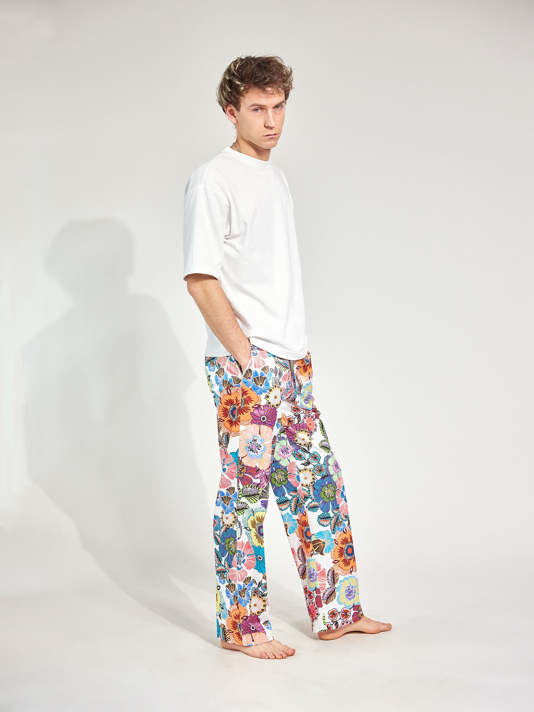 Mann trägt Hose im Pyjama-Style aus fließendem, glänzenden französischen Satinstoff und tiefen Hosentaschen