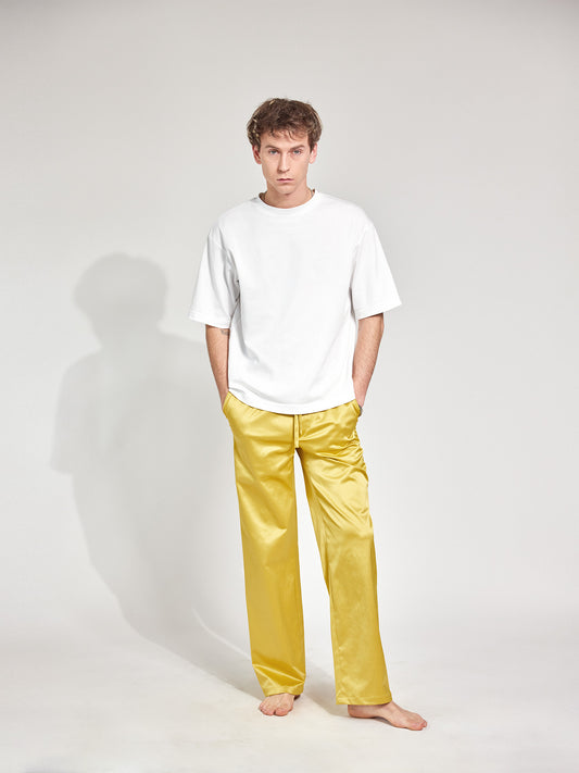 Mann trägt Hose im Pyjama-Style aus glänzendem Satin-Mix in Gold-Gelb mit tiefen Hosentaschen