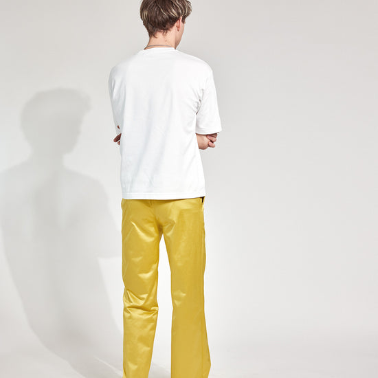 Mann trägt Hose im Pyjama-Style aus glänzendem Satin-Mix in Gold-Gelb mit tiefen Hosentaschen