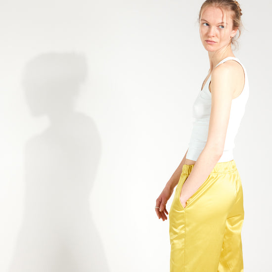 Frau trägt Hose im Pyjama-Style aus glänzendem Satin-Mix in Gold-Gelb mit tiefen Hosentaschen